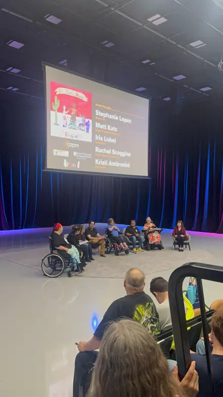 The panel seated on stage, with the storytellers' names projected on a screen behind them.